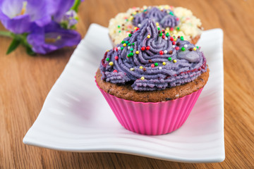  Cupcakes on white plate  decorated with berries and wild flowers