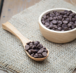 Chocolate chips in wooden spoon and bowl