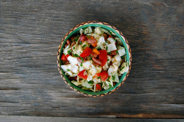 fresh tomato and cabbage salad with parsley in ceramic bowl on rustic wooden table