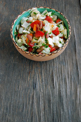 fresh tomato and cabbage salad with parsley in ceramic bowl on rustic wooden table