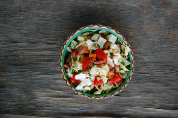 fresh tomato and cabbage salad with parsley in ceramic bowl on rustic wooden table