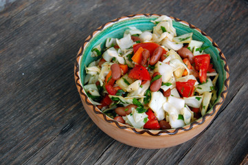 fresh tomato and cabbage salad with parsley in ceramic bowl on rustic wooden table