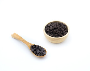 Chocolate chips in wooden spoon and bowl on white background