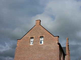 Backsteinfassade der alten Post und ehemaligen Volksschule vor Himmel mit Wolken bei Sonnenschein...