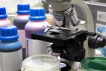 lab bench with microscopic analysis with samples and reagents / Laboratory workbench with sample in microscope, plates and reagents for microscopic analysis