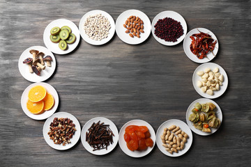 Different products on saucers on wooden table, top view