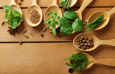 Wooden spoons with fresh herbs and spices on wooden background