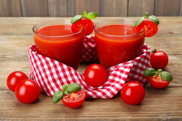 Glasses of tomato juice with vegetables on wooden background