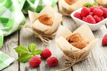 Fresh cupcakes with raspberries on grey wooden background