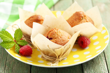 Fresh cupcakes with raspberries on green wooden background