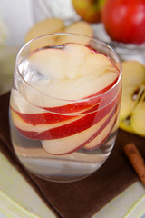 Glass of apple cider with fruits and cinnamon on table close up