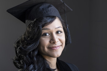 Studio graduation portrait of a young African American woman in her cap and gown, close up