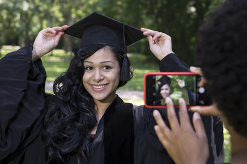 African American woman taking graduation photos in the park
