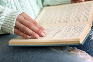Woman reading book on sofa close up