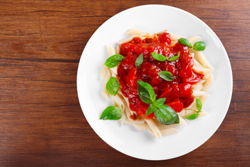 Pasta with tomato sauce and basil on wooden table close up