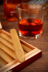 Cigars in humidor with cognac on wooden table, closeup