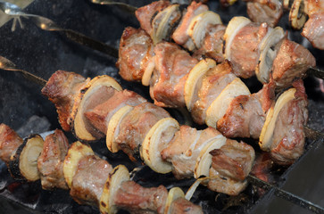 Pork meat grilling on metal skewer