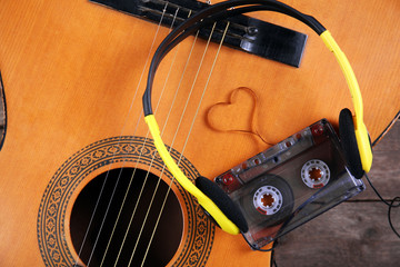 Music recording scene with guitar, cassette and headphones on wooden table, closeup