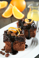 Portion of Cake with Chocolate Glaze and orange on plate, on wooden background