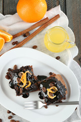 Portion of Cake with Chocolate Glaze and orange on plate, on wooden background