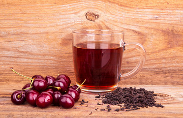 cup of tea and sweet cherry on a wooden background