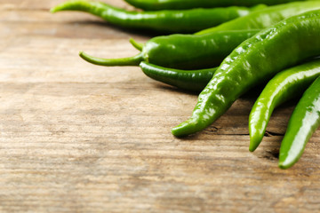 Green hot peppers on wooden table close up