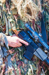 Fototapeta na wymiar A soldier in camouflage sniper holding a sniper rifle Vintorez.