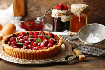 Tart with fresh raspberries, on wooden background