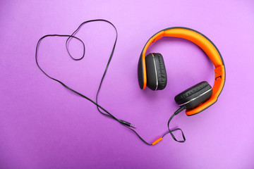 Headphones with heart of cable on purple background