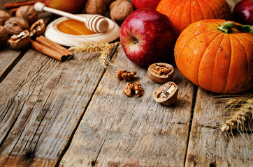 wood background with pumpkin, apples, wheat, honey and nuts