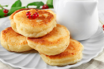 Fritters of cottage cheese with red currant in plate on table, closeup