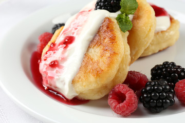 Fritters of cottage cheese with berries in plate, closeup