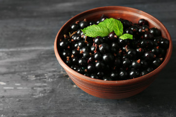 Ripe blackcurrant in bowl on wooden background