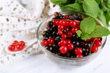 Ripe forest berries in glass bowl on light background