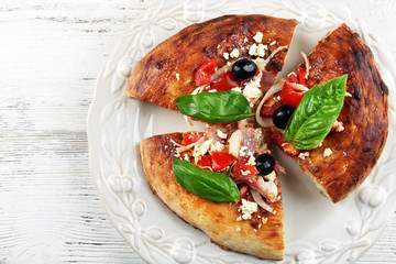 Pieces of homemade pizza on plate, on color table background