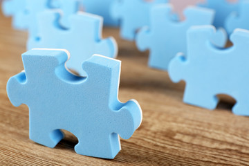 Blue puzzle pieces on wooden table, closeup