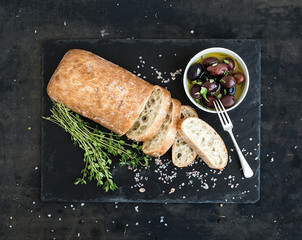 Italian ciabatta bread cut in slices on wooden chopping board - obrazy, fototapety, plakaty