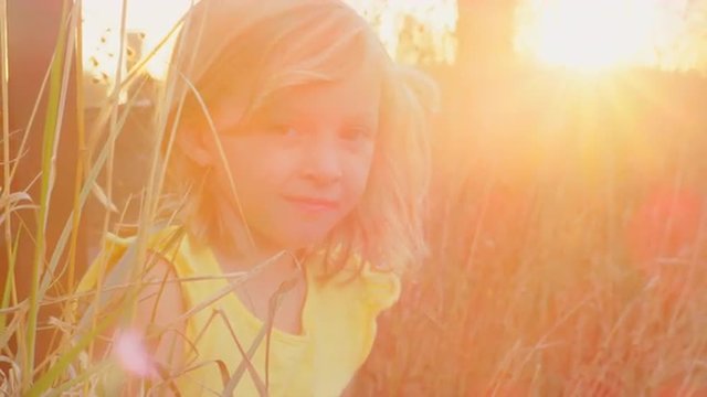 Young blonde girl sitting in grass outside