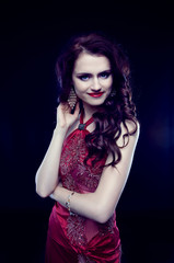 Beautiful redheaded woman with long curly hair in red evening dr