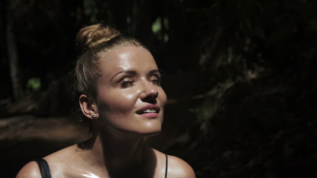 Beautiful woman standing in the jungle scene, thinking while her eyes searches for the ray of sun, shadows falling on the rest of her body creating a warm atmosphere.