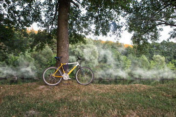 Mountain bike on the bank of the river in mist