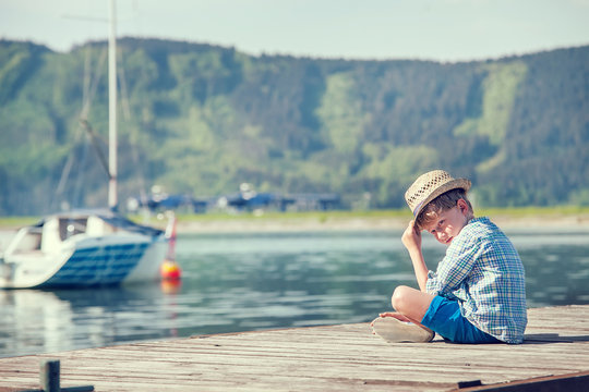 Boy sitting on wooden pier