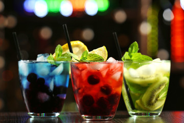 Glasses of cocktails in bar on bright blurred background