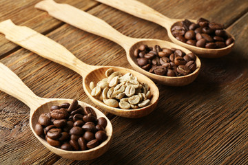 Coffee beans in spoons on wooden background