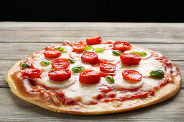 Delicious pizza with cheese and cherry tomatoes on wooden table, closeup