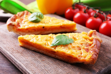 Slices of tasty cheese pizza with basil and vegetables on table close up