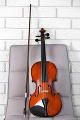 Fototapeta na wymiar Violin on chair, on bricks wall background