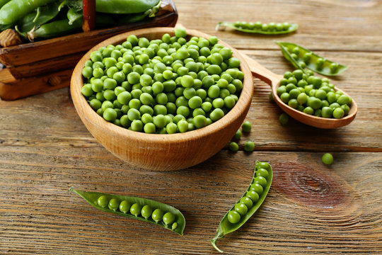 Fresh green peas in bowl and spoon on table close up