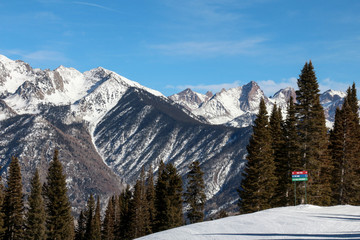 Ski hill with large mountain peaks and red, green and blue sign