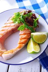 Tasty grilled salmon with greens on table close up